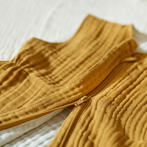 Primer plano de un saco de dormir de color mostaza con una cremallera visible en todo su cuerpo, que muestra su tejido suave y texturizado.