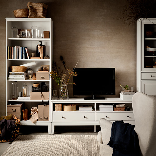 Sala de estar con estanterías blancas IDANÄS, tv y sillones beige.