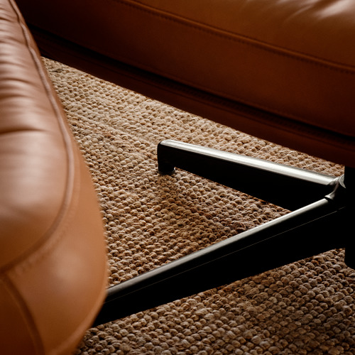 Sillón de cuero marrón en primer plano, con costuras y detalles de textura de primera calidad.