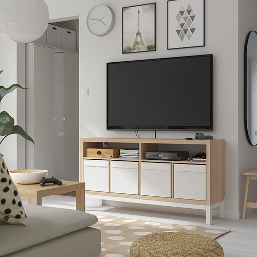 Sala de televisión minimalista con banco de televisión KALLAX, televisor de pantalla plana, accesorios para juegos, libros, sofá gris, alfombra, arte de pared, reloj, mesa de café y espejo.