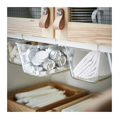 Cajón de cocina con organizadores de plástico transparente que sostienen recipientes redondos y artículos blancos en una unidad de ikea.