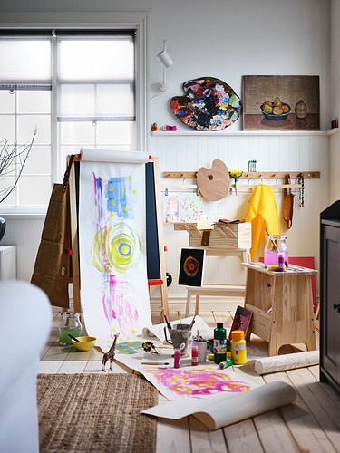 Estudio de arte con caballetes, pinturas, papeles y cuadros enmarcados.