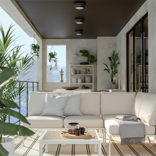 Moderna sala de estar al aire libre con sofá blanco, alfombra y plantas.