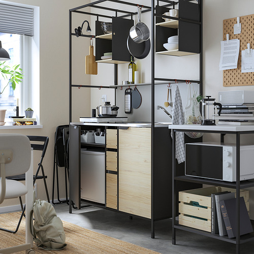 Cocina moderna con estantes de metal negro, encimera de madera, ollas, platos, microondas y sillas.