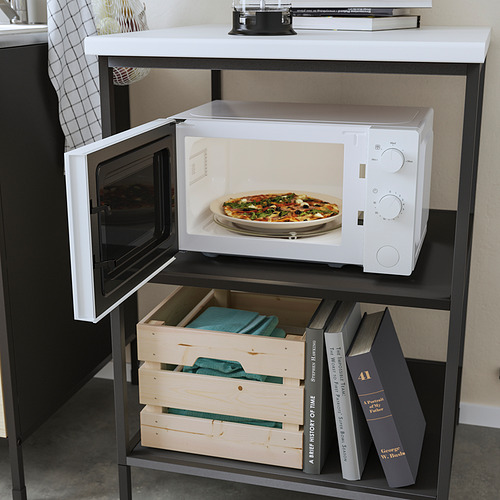 Un microondas blanco TILLREDA sobre un soporte negro, calentando una pizza. Abajo, hay libros y bandejas de madera.