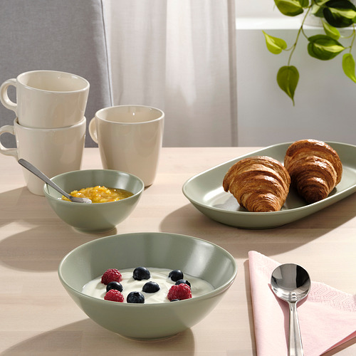 Mesa con cuencos FÄRGKLAR rellenos de yogur y frutos rojos, cruasanes y tazas para el desayuno.