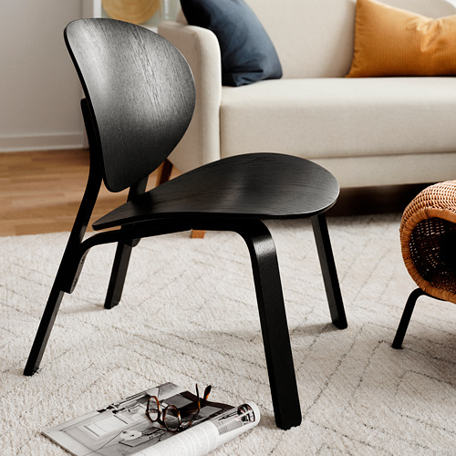 Silla de madera moderna negra cerca del sofá blanco. Elegante diseño escandinavo, líneas elegantes, minimalista.