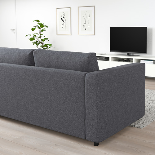 Sala de estar moderna y minimalista con un gran sofá seccional VIMLE gris oscuro, un elegante mueble de TV y arte en la pared. El tamaño de los sofás en relación con la televisión y la planta es notable.