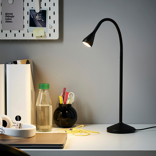 Moderno y minimalista montaje de escritorio con lámpara NÄVLINGE negra. Diseño delgado y flexible. El escritorio también contiene auriculares, botella de agua y suministros de oficina.