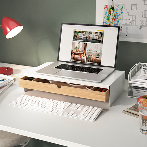 Moderna configuración de escritorio con soporte para monitor blanco y bambú ELLOVEN, computadora portátil, teclado y lámpara roja.
