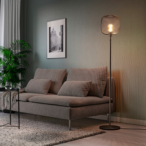Sala de estar moderna con sofá gris de mediados de siglo, lámpara de pie alta, arte y planta. La lámpara de pie es SKAFTET, base de acero, alta y estrecha.