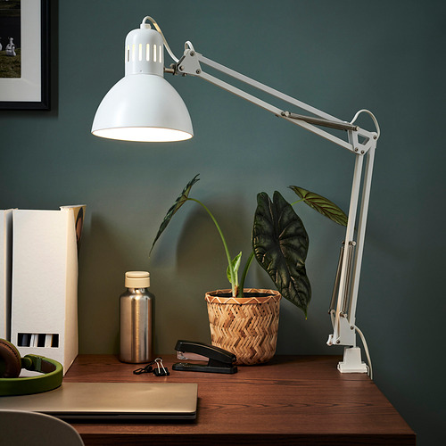 Lámpara TERCIAL blanca sobre escritorio de madera, iluminando material vegetal y de oficina.