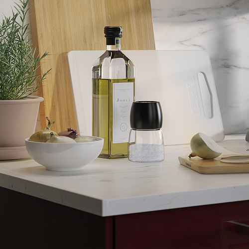 En la encimera de la cocina, el tazón con fruta se encuentra cerca de la botella de aceite y el molinillo.