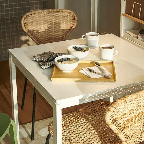 Pequeña mesa blanca con dos tazones de cereal, dos tazas de café, servilletas de tela y bandeja de madera. Ideal para desayunos sencillos y acogedores.
