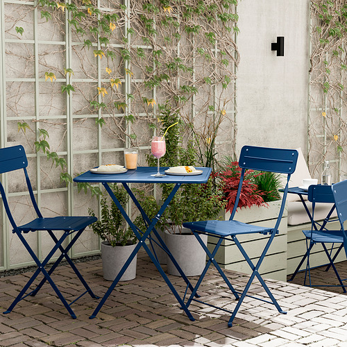 Mesa y sillas de patio azules, plegables, con plantas.