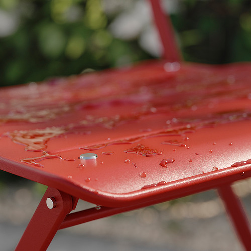 Silla de exterior de metal rojo, parte de la serie SUNDSÖ, plegada, con gotas de agua en la superficie.