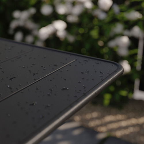 Mesa de exterior negra con gotas de agua, colocada en el exterior, parte de la serie SUNDSÖ.