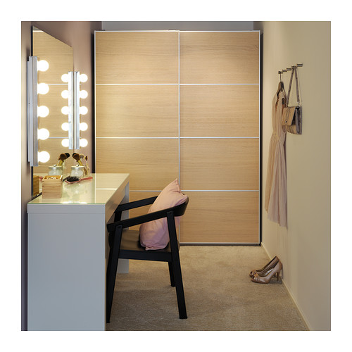 Moderno tocador con espejo iluminado, mesa blanca, silla negra y armario de madera. Pequeños accesorios dispuestos.