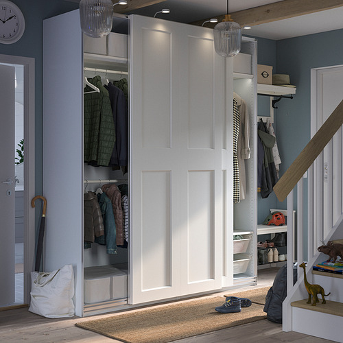 Moderno armario PAX blanco con puertas correderas, ropa y accesorios en el interior, colocado en una habitación con suelo de madera y paredes azules.