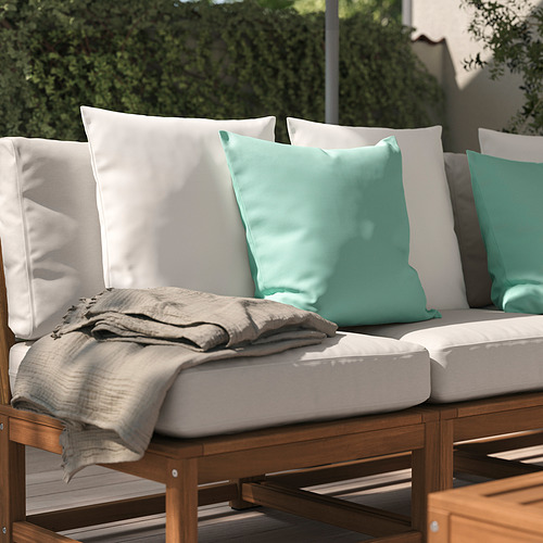 Aparte de sofá de patio al aire libre con cojines verde claro y blanco, y una manta beige.