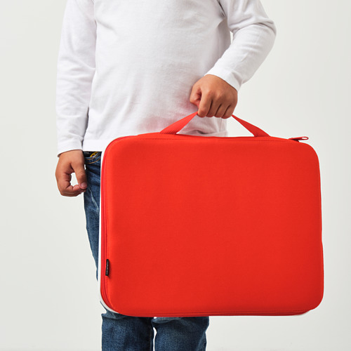 Persona que sostiene un estuche de dibujo MÅLA rojo con asa, adecuado para transportar materiales de arte.