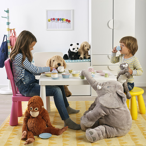 Los niños disfrutan de una fiesta de té con animales de peluche, usando una mesa del tamaño de un niño y tazas y platillos coloridos.