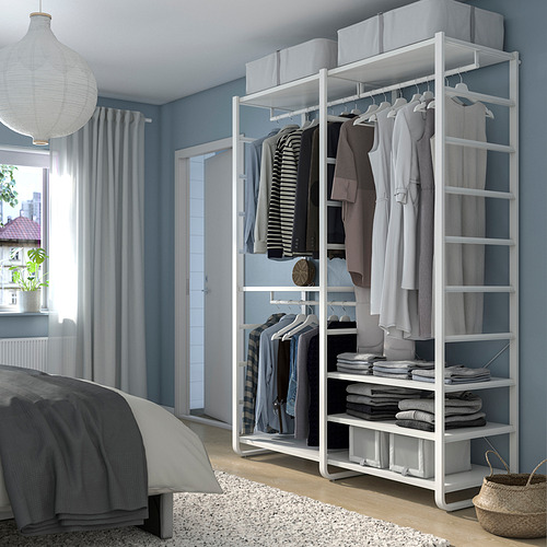 El armario blanco ELVARLI en el dormitorio guarda ropa, pliegues y accesorios, más alto que la cama, junto a la ventana.