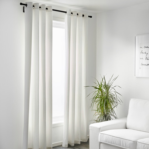 Habitación minimalista con cortinas de bloqueo de luz MERETE sobre varilla, planta y silla negras.