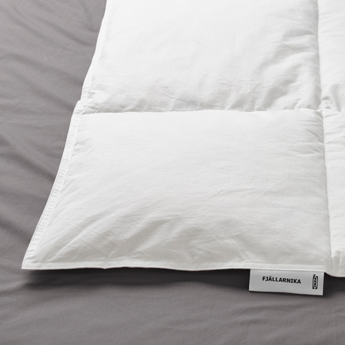 Edredón nórdico blanco sobre la cama, etiquetado FJÄLLARNIKA. Muestra tela y costuras de calidad.