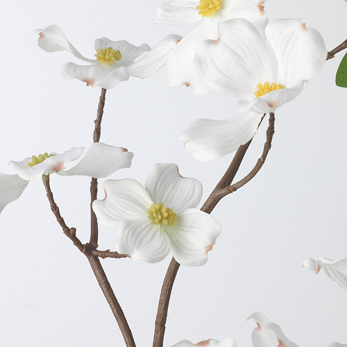 Hermosas flores blancas artificiales con centros amarillos en tallos marrones, mostrando una textura y un diseño realistas.