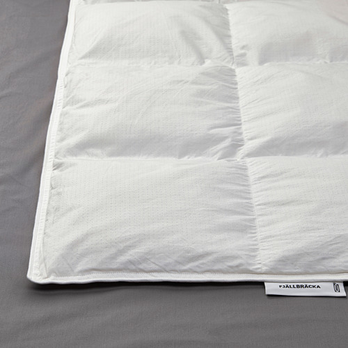 Edredón blanco limpio cuidadosamente doblado sobre ropa de cama gris. La etiqueta dice FJÄLLBRÄCKA con relleno de plumón reciclado.