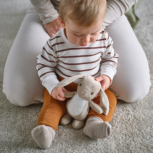 El bebé se sienta, sosteniendo un conejito de peluche, cómodo y seguro para jugar.