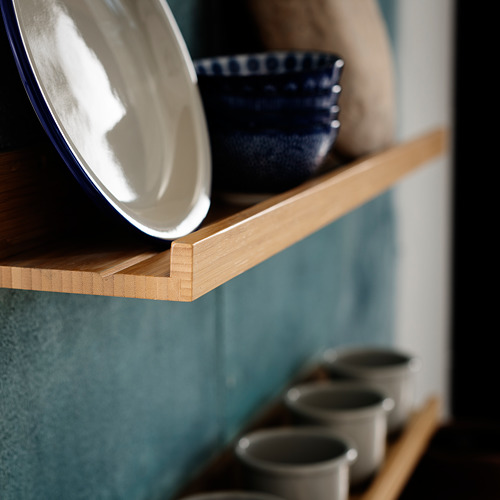 Estantes de madera que sostienen un cuenco azul y platos blancos; Almacenaje de cocina minimalista.