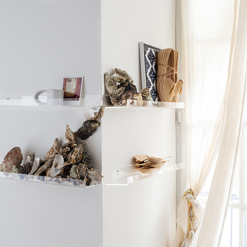 Estantes de pared de acrílico transparente que exhiben conchas marinas y cestas tejidas, ideales para exhibir artículos de decoración.