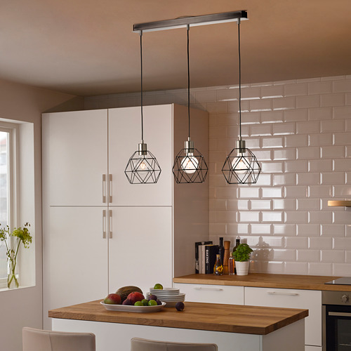 Cocina moderna con lámparas colgantes BRUNSTA blancas sobre isla de madera, sosteniendo frutero. El diseño ligero y geométrico complementa la decoración limpia y minimalista.