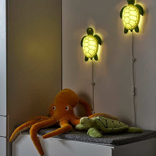 Dos apliques de tortuga que iluminan con luz suave, con pulpo de peluche y juguetes de tortugas en un estante.