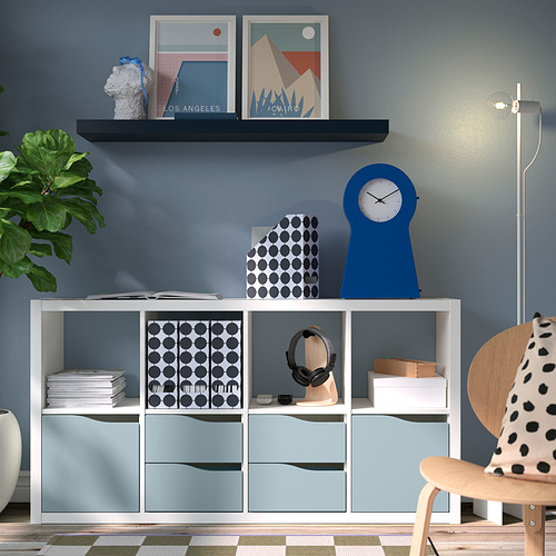 Sala de estar moderna con almacenamiento KALLAX, cajones azul claro, caja de lunares, reloj azul, estampados, plantas.
