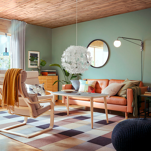 Salón moderno con paredes verdes, techo de madera, sofá naranja, sillón, alfombra, luz, espejo, mesas, plantas.
