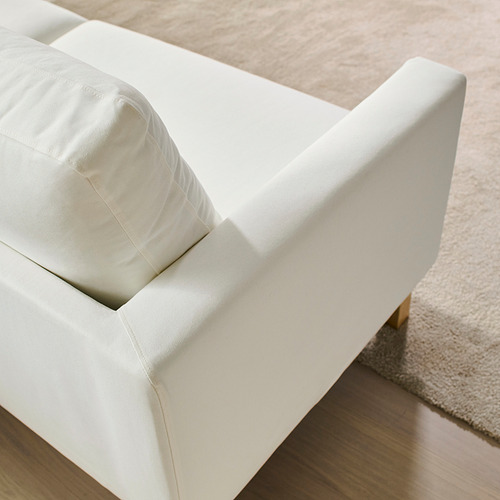 Sofá blanco minimalista moderno con líneas limpias, cojines mullidos y patas doradas elegantes sobre una alfombra acogedora.