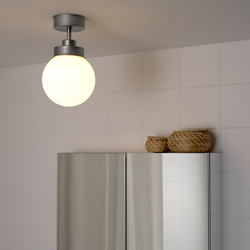 Se enciende una moderna lámpara de techo con pantalla de vidrio esmerilado, iluminando un electrodoméstico de acero inoxidable que se encuentra debajo.