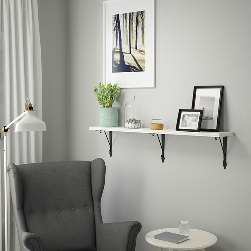 Acogedor rincón con silla orejera gris debajo de estante blanco con maceta y decoración menta.
