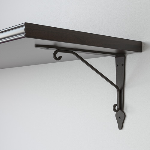 El soporte de metal negro apoya el estante de madera oscura contra una pared clara. Diseño robusto y minimalista.