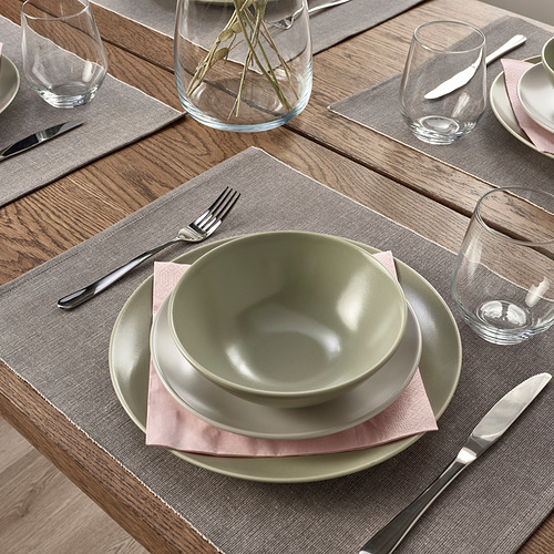 Mesa con manteles individuales SVARTSENAP grises, platos verdes, cubiertos, vasos y servilletas.