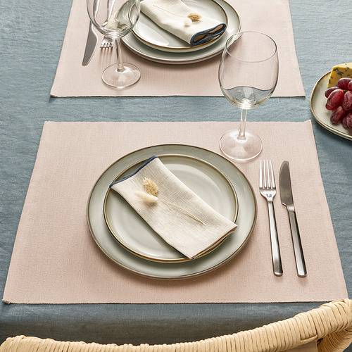 Dos platos sobre una mesa con manteles individuales, platos, vasos, cubiertos y servilletas.