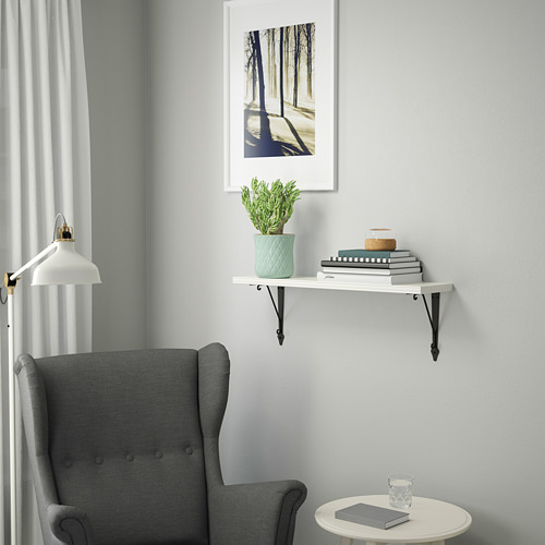 Decoración minimalista: la estantería de pared BERGSHULT contiene libros, planta cerca de la silla gris. Pequeños, blancos, rectangulares, sostenidos por soportes metálicos negros.