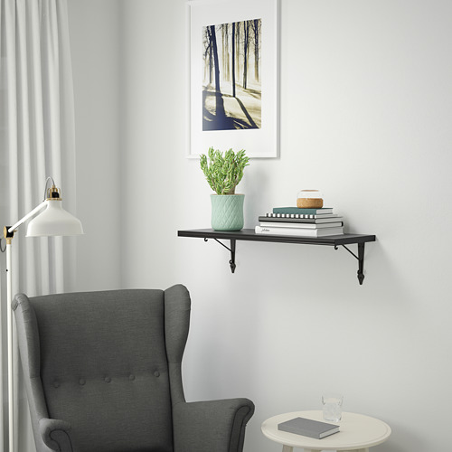 Acogedor rincón con silla, libros, planta, lámpara y estampado forestal.