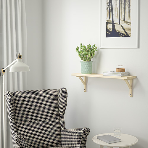 Acogedor rincón con sillón pata de gallo, mesa auxiliar, plantas y libros de pared, estampado forestal y lámpara colgante.