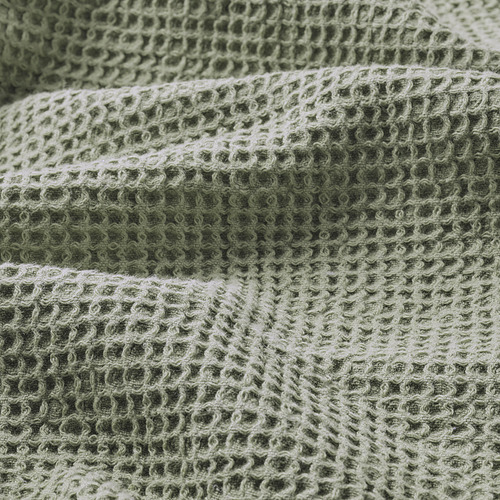 Toalla verde texturizada doblada, tejido suave con estampado de tejido waffle.