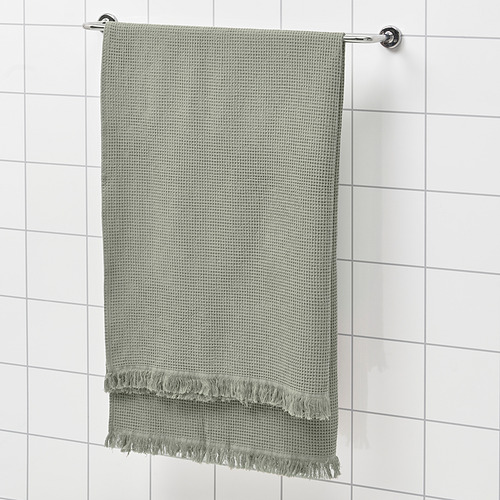 Toalla VALLASÅN verde sobre rejilla de ducha. Extremos rectangulares, texturizados, con flecos.