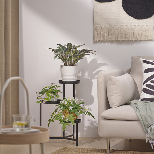 Sala de estar moderna con planta, sillón, almohadas estampadas, mesa auxiliar y arte de pared.